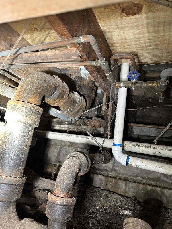 Completed site assessment of two outdoor Woodford Model 17 spigots with damaged anti-siphon devices and performed comprehensive plumbing inspection of crawlspace infrastructure. Crawlspace inspection revealed significant corrosion on older cast iron/steel piping with heavy rust accumulation, while newer PVC and copper lines appeared in serviceable condition. Documented existing plumbing conditions including mixed-age pipe materials, shut-off valve locations, and overall system configuration for future repair recommendations.