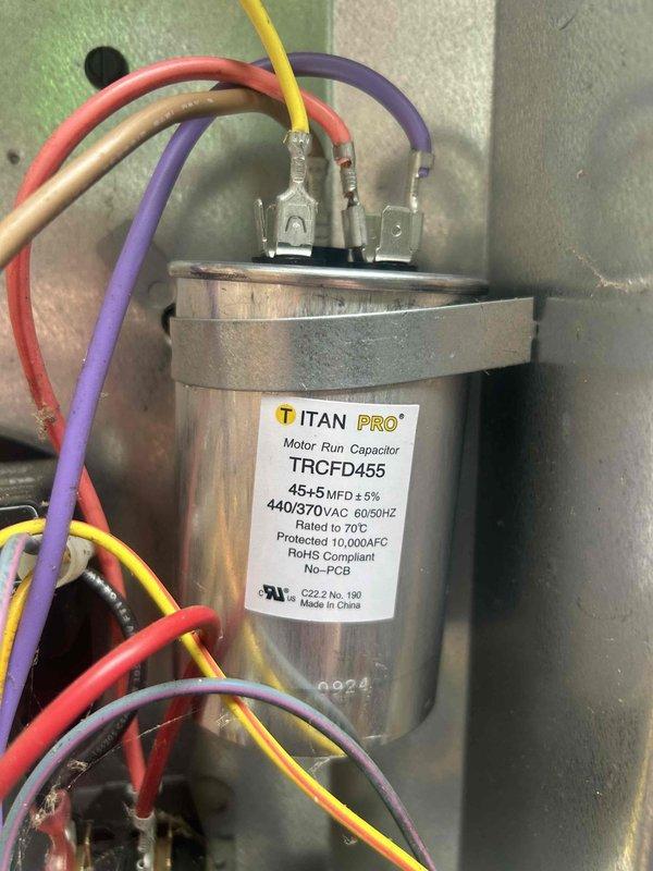 Responded to a no-cooling complaint on a 7-year-old electric air conditioning system for second opinion diagnostic evaluation. Previous contractor had diagnosed a faulty capacitor and low refrigerant charge. Upon inspection, confirmed the dual-run capacitor (TITAN PRO TRCFD455, 45+5 MFD, 440/370VAC) was operating outside acceptable parameters and required replacement. Verified all electrical connections to compressor and condenser fan motor circuits, ensuring proper wire terminations at capacitor terminals. Installed new OEM-equivalent dual-run capacitor with correct MFD ratings for both compressor and fan motor operation. Tested system operation following capacitor replacement, confirming proper compressor start-up, condenser fan motor function, and adequate amp draw on both circuits. System returned to normal cooling operation with proper temperature differential across evaporator coil. Refrigerant charge assessment indicated levels within manufacturer specifications, requiring no ad