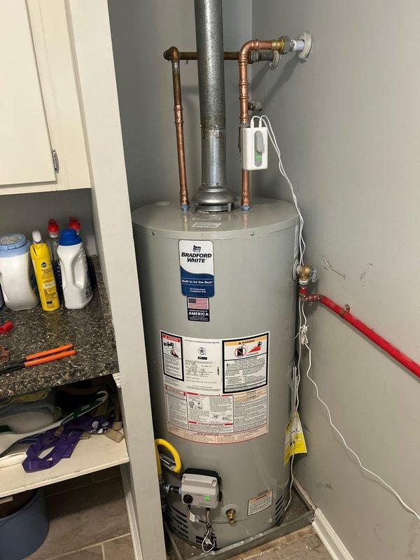 Completed installation of 40-gallon Bradford White gas water heater in residential utility closet. Drained and removed existing water heater, then installed new unit with proper copper piping connections and brass fittings. Connected gas line and water supply lines to new tank, pressure tested all connections to verify no leaks present. Installed and secured metallic vent flue for proper exhaust ventilation. Additionally installed Resideo WiFi Leak & Freeze detector for system monitoring. Tested water heater operation to confirm proper ignition, heating function, and temperature control. Provided homeowner with tutorial on mobile app setup and operation for the WiFi leak detector. Verified all safety features functioning correctly before completing installation.