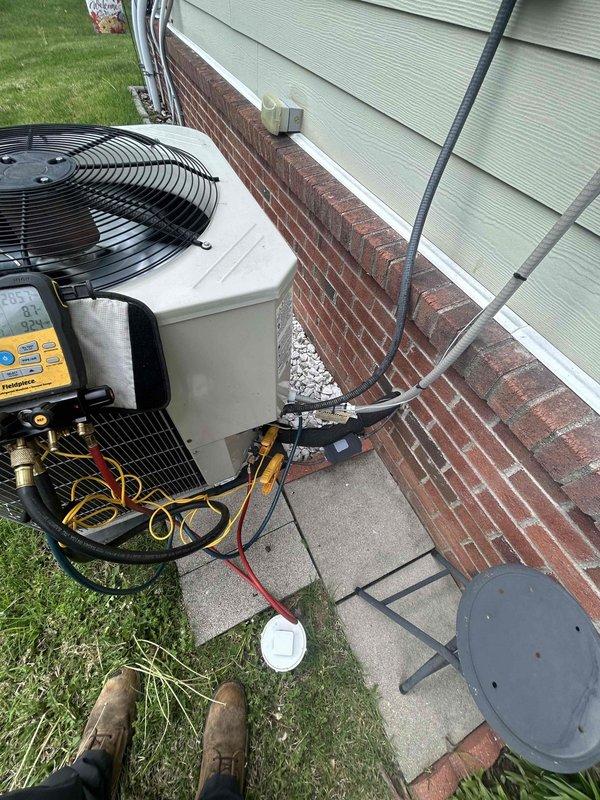 Performed routine monthly club maintenance on residential heat pump system with air handler located above garage. Conducted comprehensive spring/summer inspection including refrigerant pressure and temperature diagnostics using digital manifold gauges on outdoor condensing unit. Connected testing equipment to service ports to verify proper system operation, refrigerant charge levels, and overall unit performance. Inspected condenser unit positioned on concrete pad adjacent to building, checking electrical connections, refrigerant lines, and mechanical components for proper function and wear. System operating within normal parameters with no deficiencies noted during this scheduled preventive maintenance visit.
