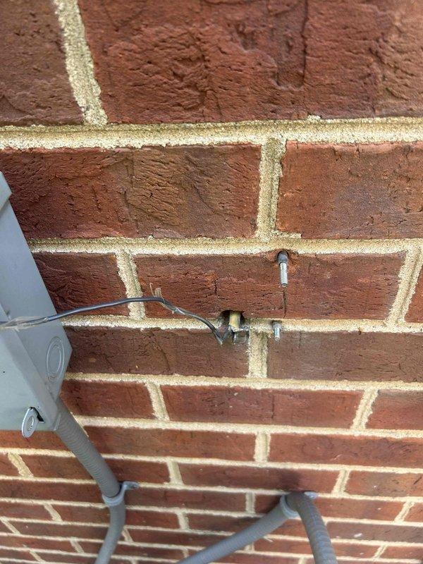 Responded to no cooling complaint on commercial electric HVAC system over 20 years old with indoor unit located in utility closet. Upon arrival, coordinated with maintenance personnel regarding reported wiring issues. Performed diagnostic inspection of electrical connections at exterior disconnect boxes serving units 30 and 101. Documented existing electrical conduit routing and connection points between exterior disconnects and equipment. Inspected exterior utility connections and associated gas line penetrations through brick wall. Photographed electrical installation configuration for service records.