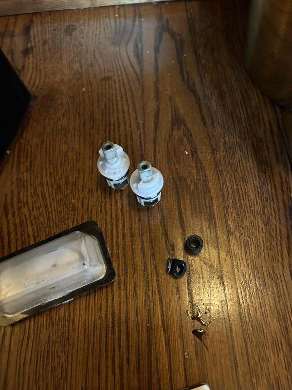 Responded to dripping faucet in half bath. Disassembled ornate brass three-piece faucet assembly with porcelain handles mounted on black countertop. Replaced worn valve cartridges and internal seals that were causing the drip. Reassembled faucet, tested both hot and cold water controls, and verified complete elimination of leak with no dripping present.