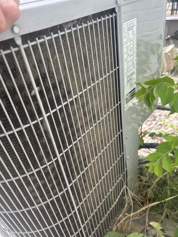 Responded to no-cool complaint on 14-year-old electric air conditioning system that was reportedly unable to maintain temperature setpoint. Previous contractor had diagnosed failed compressor and recommended full system replacement. Upon arrival, performed visual inspection of outdoor condensing unit and discovered severely restricted condenser coil with heavy accumulation of dirt, dust, and debris completely blocking airflow through fins. Coil contamination was preventing adequate heat rejection, causing system to run continuously without achieving desired cooling. Documented condition with photographs showing extent of buildup behind protective grille. Recommended thorough condenser coil cleaning to restore proper airflow and system operation before pursuing compressor replacement, as restricted airflow can mimic compressor failure symptoms.