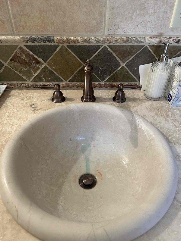 Responded to customer request to retain existing oil-rubbed bronze three-piece bathroom faucet instead of replacing with supplied model. Accessed under-sink plumbing through vanity cabinet and replaced defective internal faucet components including cartridges and seals while preserving original fixture to maintain aesthetic match with bathroom décor. Verified proper water flow and tested both hot and cold supply lines for leaks after reassembly. All plumbing connections secured and operational.