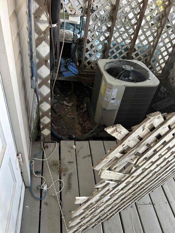 Responded to no cool call on electric heat pump system with indoor air handler located in walkout basement. Upon arrival, customer reported system not reaching thermostat setpoint. Performed visual inspection of Bryant indoor air handler unit and outdoor condensing unit. Observed outdoor condenser positioned on ground level adjacent to wooden deck with weathered surrounding area. Indoor unit installation appeared standard with proper electrical connections, PVC condensate drainage, and APCO air purification device installed on ductwork. Checked system operation and airflow at indoor unit. Documented equipment condition through photographs for service records. System requires further diagnostic testing to determine root cause of insufficient cooling capacity and inability to satisfy thermostat demand.