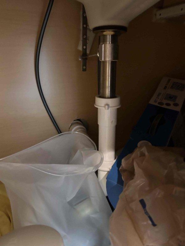 Completed routine 60-point plumbing inspection per customer request with 30-minute advance notification provided. Performed comprehensive visual assessment of under-sink plumbing configuration, including white PVC trap assembly, chrome tailpiece, and sink drain basket connections. Inspected all accessible pipe joints, mounting brackets, and drain components for signs of leaks, corrosion, or deterioration. Verified proper drainage function and confirmed all plumbing fixtures were secure and operating within normal parameters. Documented findings with photographic evidence showing cabinet interior conditions and plumbing infrastructure. No immediate repairs required at time of inspection.