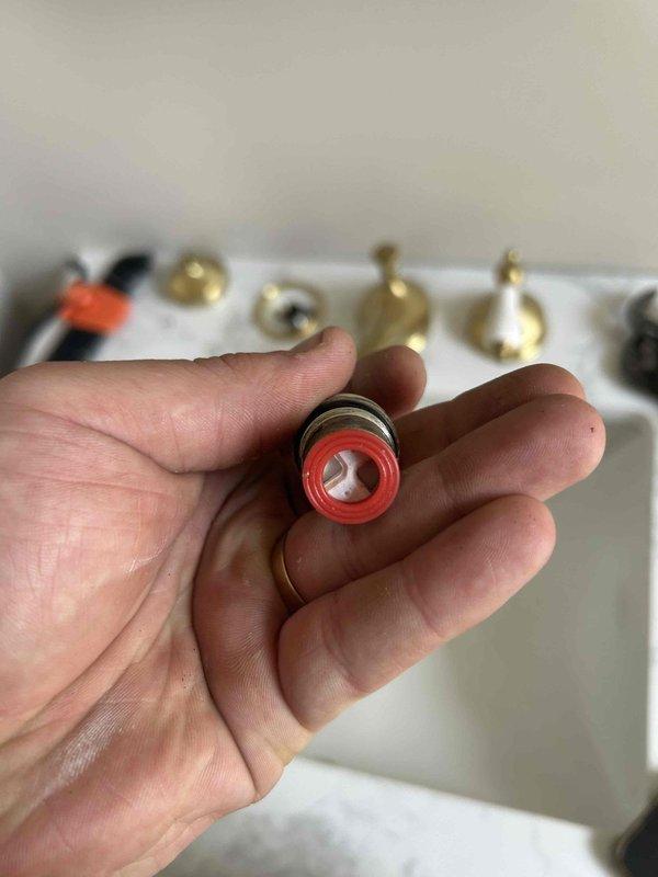 Responded to service call for downstairs bathroom faucet with no hot water production. Upon arrival, coordinated property access through realtor. Diagnosed issue as failed cartridge in hot water valve assembly of three-handle widespread bathroom faucet with brass finish. Disassembled hot water control valve, removed defective cartridge containing worn internal seals and O-rings. Installed replacement cartridge assembly, ensuring proper seating and alignment within valve body. Reassembled faucet handle with porcelain accent piece and tested operation. Verified full hot water flow restoration and proper temperature mixing capability. Faucet now operating correctly with balanced hot and cold water delivery.