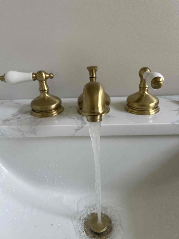 Responded to service call for downstairs bathroom faucet with no hot water production. Upon arrival, coordinated property access through realtor. Diagnosed issue as failed cartridge in hot water valve assembly of three-handle widespread bathroom faucet with brass finish. Disassembled hot water control valve, removed defective cartridge containing worn internal seals and O-rings. Installed replacement cartridge assembly, ensuring proper seating and alignment within valve body. Reassembled faucet handle with porcelain accent piece and tested operation. Verified full hot water flow restoration and proper temperature mixing capability. Faucet now operating correctly with balanced hot and cold water delivery.