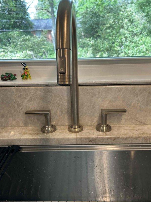 Completed kitchen sink faucet replacement on return visit. Successfully installed modern three-piece faucet system with pull-down spout and dual lever handles in brushed stainless steel finish. Connected all supply lines and verified proper operation with no leaks detected beneath undermount sink installation.