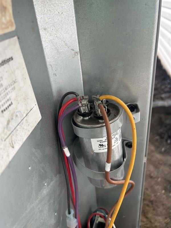 Responded to no heat call on 5-year-old Bryant heat pump system that stopped producing warm air overnight. Upon arrival, performed diagnostic inspection of outdoor condenser unit and electrical components. Inspected capacitor and associated wiring connections, including red, purple, brown, and yellow wire terminals. Verified proper electrical connections to capacitor terminals and checked component condition. System evaluated and capacitor inspected for proper operation to restore heating functionality to the heat pump unit.