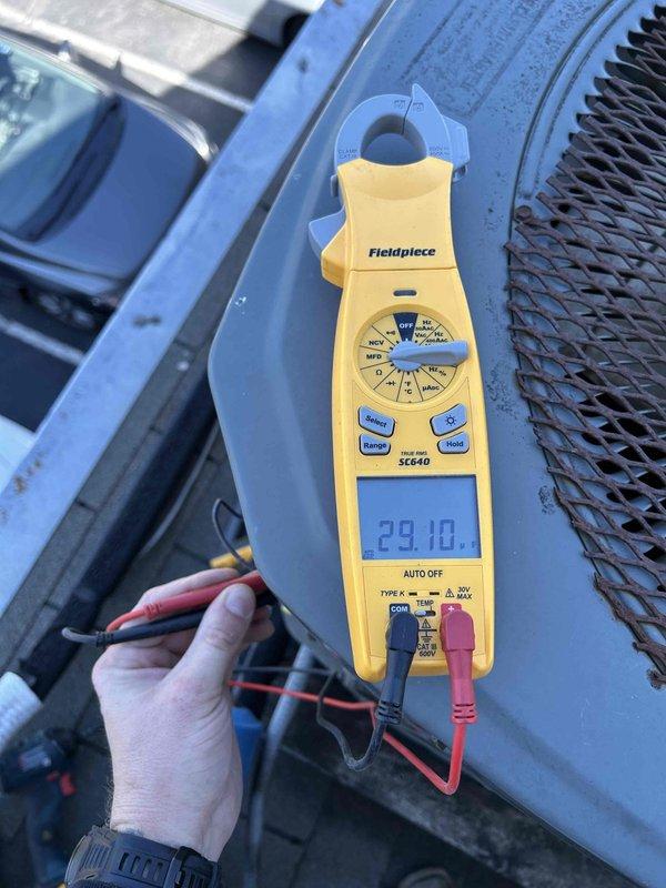 Completed comprehensive Care Plan tune-up on dual-zone HVAC system including ground floor air conditioning unit located in crawlspace, heat pump/air handler in attic, and outdoor condenser unit on rooftop with interior access. Performed full system diagnostics using clamp meter to verify electrical readings and amperage draws on all equipment, confirming proper operation at 29.10 amps on tested circuit. Replaced 20x20x1 air filter (X6670 model included in maintenance plan), inspected all accessible components, and documented equipment condition with diagnostic photos showing proper electrical values and clean equipment operation across all system zones.