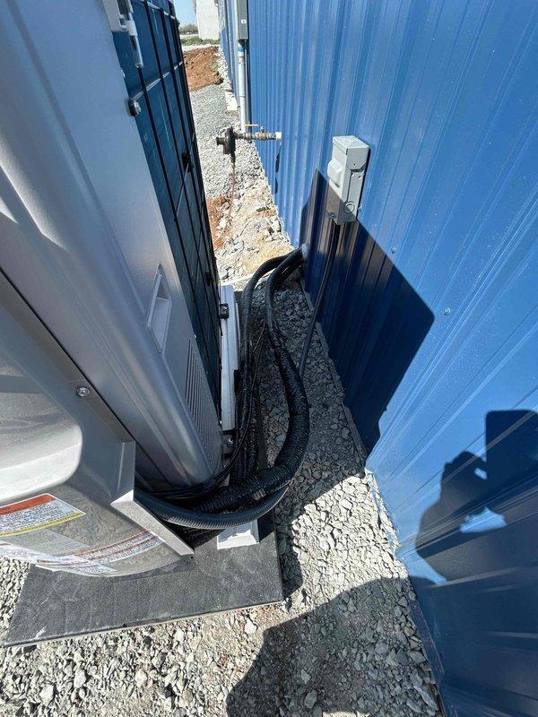 Successfully installed a Friedrich 24K BTU low-temperature mini split system consisting of a ProX Series outdoor condenser unit (FPHFR24A3D) and indoor wall mount air handler (FAHFW24A3D) with refrigerant line set. The outdoor unit was mounted on a composite pad with isolation base in a confined service area between buildings, complete with electrical disconnect box, whip kit, snow legs, and insulated refrigerant lines routed through the building wall, with main electrical connection to be completed by others per scope.