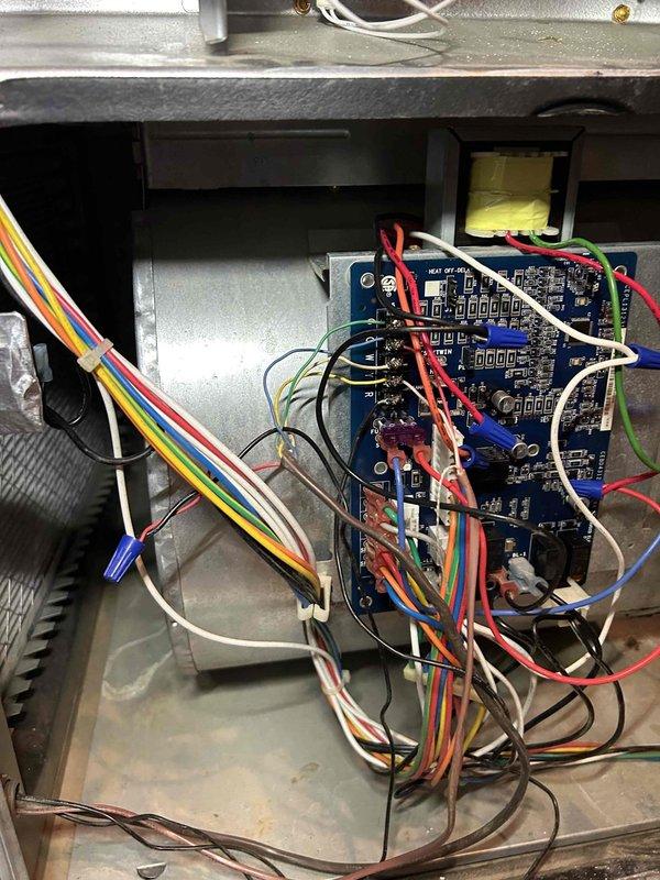 Responded to service callback for HVAC unit repeatedly burning out transformers. Upon arrival, performed diagnostic inspection of control board and blower motor assembly following previous electrical system clearance by electrician. Utilized digital temperature measurement device to assess operating conditions and thermal readings throughout the unit. Conducted thorough examination of the circuit board, verifying all wire connections, terminals, and relay functions. Inspected blower motor for signs of overheating, excessive amp draw, or mechanical binding that could cause transformer failure. Evaluated all power connections, including red and black power leads to control board. Assessed condition of multi-colored wiring harnesses and ribbon cables for any signs of shorts, fraying, or improper connections. Documented current system conditions with photographs showing control board configuration, internal wiring layout, and temperature readings. Unit interior showed normal dust accumulat