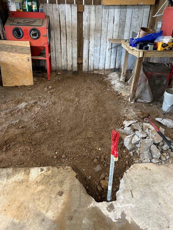 Excavated approximately 15 feet of water line from the meter to locate and access the existing supply line using an excavator. Dug interior trench inside barn structure through dirt floor to establish routing for new hydrant installation. Installed white PVC supply line running the length of the exterior trench and connected new yard hydrant at terminus point near barn structure.
