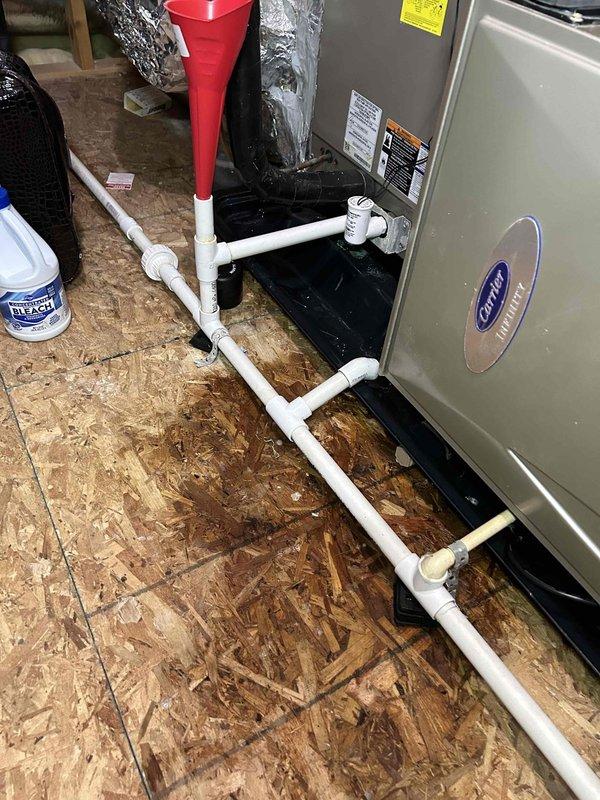Responded to emergency water leak call where condensate drain pan was overflowing from attic-mounted Carrier air handler, causing water intrusion into ceiling below. Upon inspection, found primary condensate drain line clogged, preventing proper drainage and causing auxiliary drain pan to overflow. Cleared blockage from condensate drain system using appropriate methods, verified proper flow and drainage through PVC piping, and confirmed drain pan was functioning correctly with no further overflow. Tested system operation to ensure condensate was draining properly and no additional leaks were present.