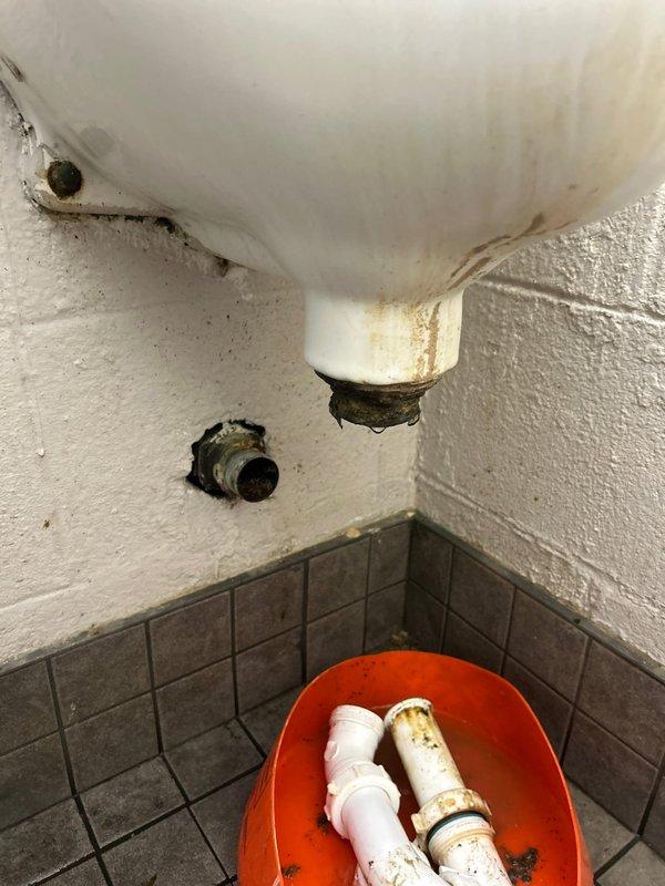 Responded to commercial warehouse for actively leaking toilet. Upon diagnosis, identified failed Sloan flush valve assembly causing water leak at wall-mounted connection point. Removed deteriorated valve components showing significant corrosion and rust staining on wall surfaces. Replaced defective flush valve with new Sloan assembly, restoring proper operation and eliminating active leak.