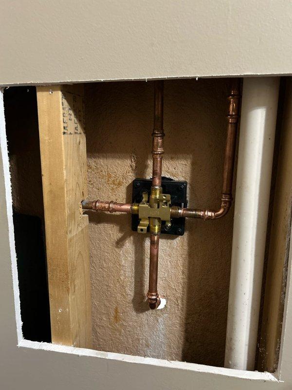 Replaced existing shower valve with customer-supplied Delta valve and trim, requiring access panel creation by cutting drywall behind shower wall to reach plumbing assembly. Installed new waste and overflow assembly for bathtub drainage system. Connected valve to existing copper supply lines, secured mounting plate, and installed chrome trim components including single-handle diverter valve and tub spout. Verified proper water flow, temperature control, and drainage functionality upon completion, then removed old parts and debris from work area.