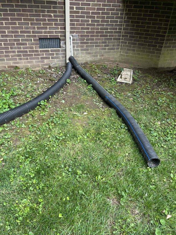 Completed warranty return to re-route condensate drainage system for freeze prevention. Installed 3/4" PVC piping through exterior wall with tee fitting and standpipe vent at top to allow proper drainage and prevent freeze-ups. Added 3/8" vinyl tubing with loop configuration before PVC connection as additional freeze protection measure. Removed existing condo tubing from drain line and sealed opening with silicone as temporary solution pending plumbing contractor's permanent repair work.