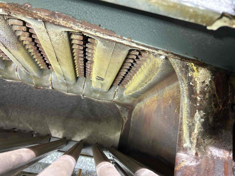 Completed routine maintenance tune-up on 48-year-old residential boiler system during early morning service window. Performed comprehensive inspection of burner assembly, revealing significant age-related deterioration including heavy corrosion, rust accumulation, and debris buildup on burner tubes and heat exchanger components. Documented advanced oxidation on evaporator coil fins with extensive reddish-brown patina and material degradation from prolonged moisture exposure. Cleaned accessible components and verified operational functionality. Advised customer of equipment's advanced age and deteriorating condition, recommending consideration for system replacement due to compromised efficiency and potential safety concerns associated with corroded heat exchanger surfaces.