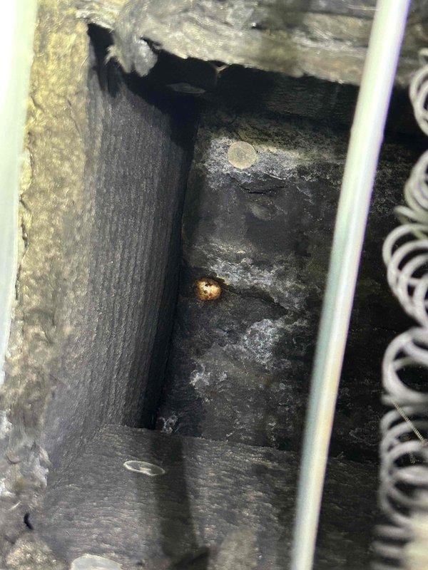 Responded to call back for ongoing water leak investigation. Inspected HVAC unit and surrounding areas to locate source of moisture issue. Upon examination, found drain pan area with significant accumulation of dust, dirt, and debris that had built up over extended period, potentially restricting proper drainage. Observed PVC condensate drain line routing through wall cavity with spray foam insulation present. Documented conditions with photos showing heavily soiled interior compartment and drain line configuration. Verified drain pan integrity and condensate line connections for signs of cracks or damage that could cause water leakage.