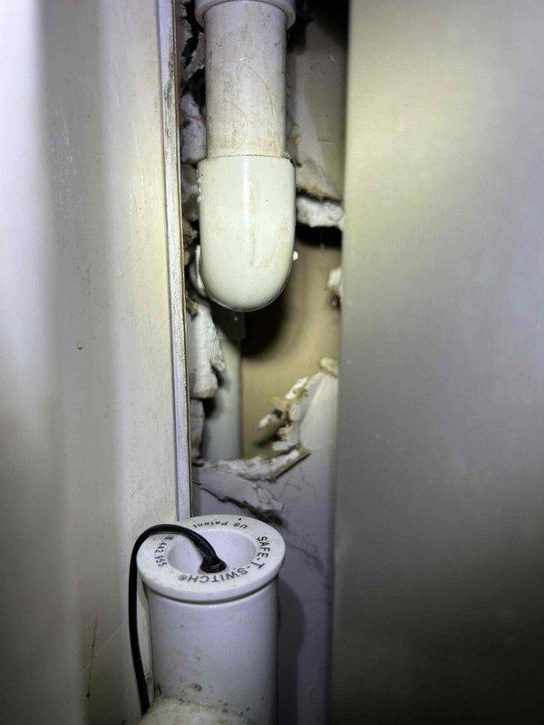 Responded to call back for ongoing water leak investigation. Inspected HVAC unit and surrounding areas to locate source of moisture issue. Upon examination, found drain pan area with significant accumulation of dust, dirt, and debris that had built up over extended period, potentially restricting proper drainage. Observed PVC condensate drain line routing through wall cavity with spray foam insulation present. Documented conditions with photos showing heavily soiled interior compartment and drain line configuration. Verified drain pan integrity and condensate line connections for signs of cracks or damage that could cause water leakage.