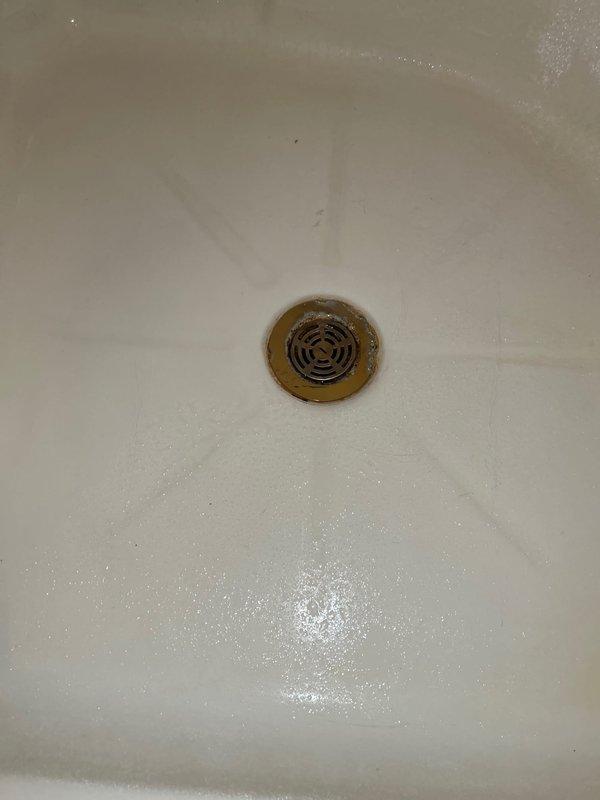 Completed routine plumbing inspection of residential property. Examined bathtub drain assembly, noting mineral buildup and rust-colored staining around drain rim consistent with normal aging and hard water deposits. Inspected water heater installation in utility closet, verifying proper positioning, venting configuration with flexible metal conduits, and confirming all manufacturer labels and safety warnings remain visible and intact.
