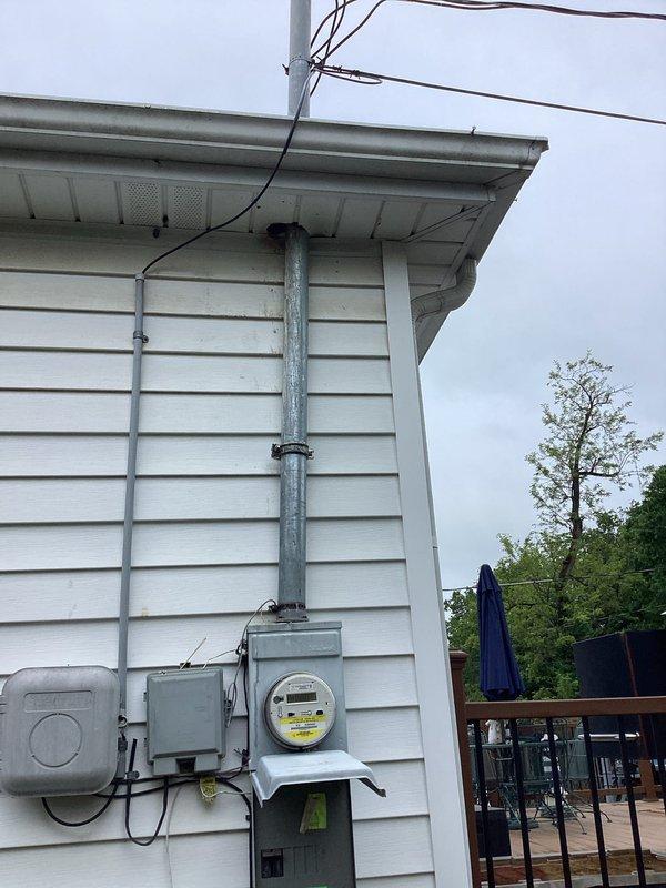 Conducted comprehensive site evaluation for backup generator installation at residential property. Documented existing electrical service entrance configuration, including weatherhead connection, exterior meter base with digital display, and main service panel location on exterior wall. Assessed interior main electrical panel capacity and current circuit breaker configuration to determine available amperage and compatibility for generator transfer switch integration. Photographed existing electrical infrastructure including service entrance conductors, meter socket mounting, panel bus configuration, and existing branch circuit wiring to develop accurate material and labor estimates for 10-12 kW standby generator system installation with automatic transfer switch.