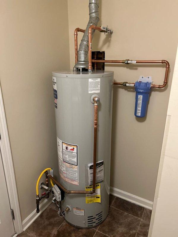 Replaced existing water heater with new Bradford White 40-gallon gas tall tank unit in residential utility closet. Installed customer-supplied in-line water filtration system with blue Culligan filter housing, integrated into copper supply line configuration using proper fittings and shut-off valves. Connected all hot and cold water lines, installed yellow flexible gas line to unit, and completed proper venting installation with gray vent piping. All connections tested and verified operational with no leaks detected.