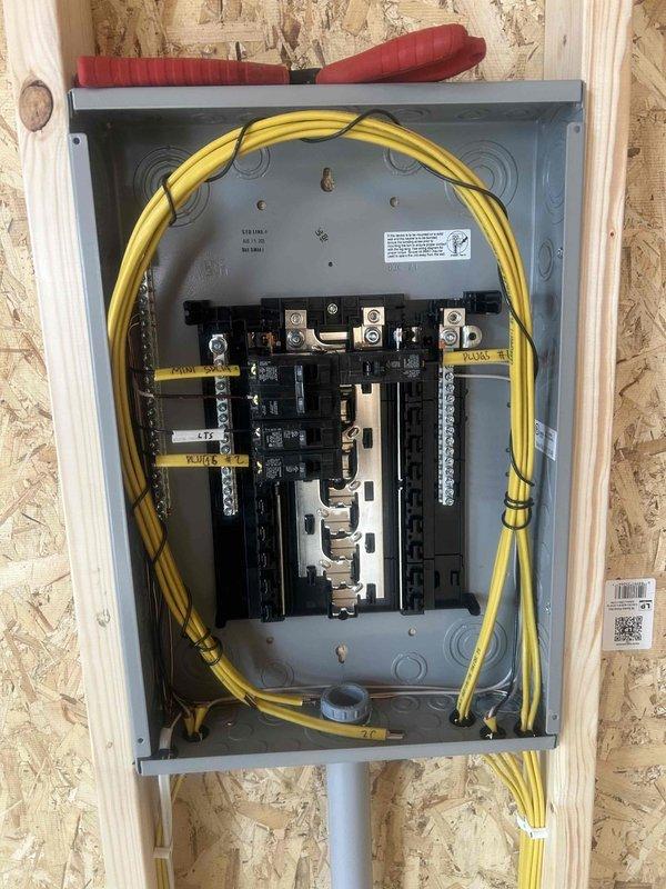 Completed full electrical rough-in installation for commercial structure, including installation and wiring of 12-space 100-amp main service panel with 1-115V, 7-120V, and 1-215V breakers using 1¼" conduit as specified. Installed dedicated 240V 15-amp circuit for air conditioning unit using 12-2 wire, along with comprehensive receptacle package consisting of 3 GFCI outlets, 7 duplex receptacles, 1 floor plug, and 2 weatherproof exterior receptacles. Completed rough-in wiring for lighting system including 2 exterior sconces, 2 surface-mounted lights, 1 ceiling fan/light combination, and 1 dusk-to-dawn flood light fixture, with customer-supplied fixtures to be installed at later phase. Installed switching infrastructure including 2 three-way switch locations and 4 single-pole switches for lighting control throughout the space. All wiring runs completed through exposed stud framing in accordance with NEC requirements, with circuits properly labeled and organized within panel for clear ide