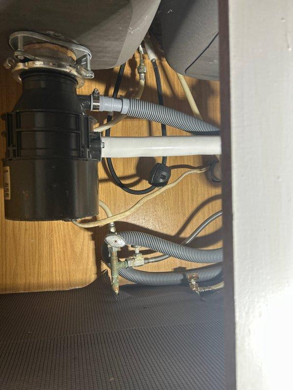 Responded to service call for leaking faucets in bathroom tub and kitchen sink. Inspected chrome bathtub faucet assembly and diverter valve for signs of wear and water damage, noting visible spotting on fixtures indicating active leak conditions. Evaluated under-sink plumbing connections at kitchen sink, examining garbage disposal unit, drainage lines, and flexible supply hoses for potential leak sources. Addressed leak issues at both locations to restore proper function and eliminate dripping.