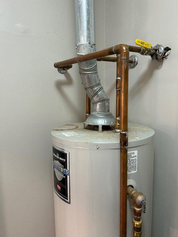 Responded to water leak above Bradford White water heater originating from vent system in laundry room utility closet. Upon inspection, identified active leak at vent pipe connection and draft diverter assembly above unit. Assessed copper supply lines, brass fittings, and galvanized venting system for source of moisture intrusion. Documented existing water heater installation including plumbing configuration, gas shut-off valve, pressure relief valve, and vent pipe routing. Provided assessment of current system condition and prepared replacement quote per customer request.
