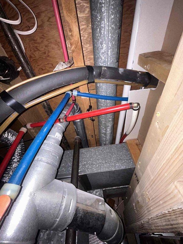 Completed comprehensive plumbing inspection of unpermitted basement bathroom installation to verify code compliance for real estate transaction. Examined all visible plumbing components including supply lines, drain waste vent system, pipe materials, connections, and installation methods throughout the mechanical space. Documented findings with photographic evidence showing copper supply piping, PVC drainage system, water heater connections, and HVAC integration within the confined utility area between floor joists and wall framing.