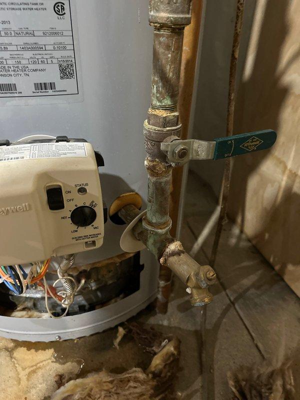 Responded to water leak at basement water heater with steady flow occurring when water was in use. Upon inspection, identified leak source at hot water recirculation system components, specifically at the Grundfos circulator pump connections and associated copper piping. The aged copper plumbing showed significant corrosion, mineral deposits, and patina formation at multiple threaded fittings and joints. Documented the condition of the water heater installation, including the Honeywell control unit, ball valve assembly, and deteriorated pipe connections where water infiltration was occurring during system operation.