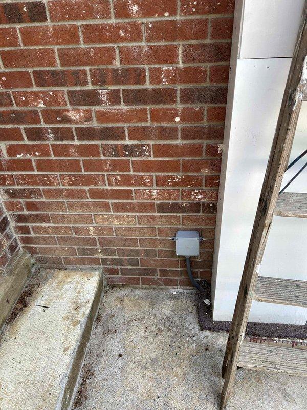 Completed first phase of two-trip mini split electrical service for sunroom addition. Removed existing exposed wiring from brick wall and properly terminated connections in new junction box mounted to exterior masonry. De-energized and secured dedicated breaker at panel to ensure safety during construction phase. Homeowner advised to schedule second trip after roof installation but before interior finishing to allow proper wire routing through framing. Second trip will involve running new circuit in conduit up brick wall, through new ceiling construction, and terminating at existing mini split disconnect location.
