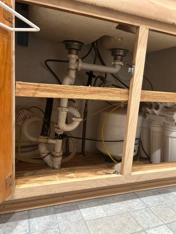 Responded to service call for multiple plumbing issues including kitchen sink leak, shower seal requirement, and low water pressure at bathroom sink. Upon inspection, identified steady leak originating from under-sink area where APEC water filtration system and associated plumbing connections are installed. Examined dual-drain P-trap assembly, supply lines, and filter housing connections for signs of moisture and active leaks. Assessed water filtration system components including multi-stage filter canisters, pressurized storage tank, and connecting tubing for proper sealing and potential failure points. Inspected chrome drain assemblies, PVC trap configuration, and flexible supply hoses for compromised seals or loose connections. Documented existing plumbing infrastructure and filtration system layout for repair planning. Evaluated shower area requiring seal work and investigated bathroom sink low pressure issue to determine if related to main filtration system or isolated fixture pro
