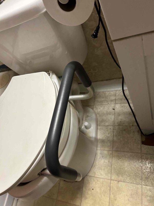 Responded to service call for non-functional toilet with disabled flush handle. Upon arrival, found water supply had been shut off due to previous flooding incident that occurred when toilet was lifted. Assessed toilet condition and accessibility features, noting wall-mounted tank configuration with safety grab bar installation. Inspected flexible water supply line connection and verified shut-off valve position. Documented existing conditions including floor tile wear patterns and overall fixture placement in accessible bathroom setting.