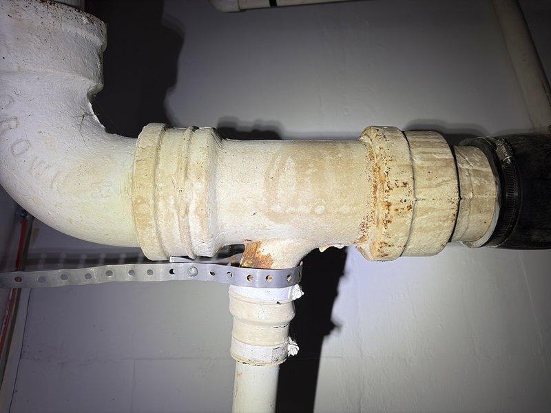 Conducted comprehensive plumbing assessment based on home inspection findings, identifying multiple critical issues requiring attention. Documented extensive corrosion and rust at drainage lines, active leaks at both supply lines and waste drainage connections, and missing or inaccessible clean-out access point. Evaluated gas water heater installation, noting insufficient vent flue rise with negative slope and absence of required drip pan beneath unit. Photographed corroded pipe joints, deteriorated connections with visible rust staining, and compromised drainage system components to support estimate preparation for necessary repairs and code compliance updates.