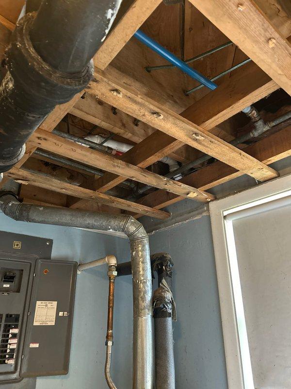 Responded to low water pressure complaint in guest bathroom affecting sink and bathtub, with particulate material present in tub water. Inspected exposed plumbing infrastructure in basement area, examining supply lines, aging cast iron drainage pipes, and water distribution system. Identified sediment buildup and potential issues with galvanized piping contributing to reduced flow and water quality concerns. Documented existing plumbing configuration including copper supply lines, flexible connectors, and various pipe materials showing age-related deterioration that may be impacting water pressure and introducing particulates into the system.