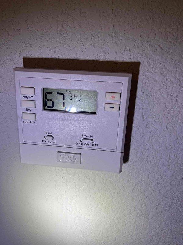 Responded to no cooling complaint on 2-year-old electric HVAC system that had been inoperative for several weeks. Performed diagnostic evaluation of indoor unit located in front door closet. Inspected thermostat operation showing 67°F display reading with system set to cooling mode, verified thermostat programming and control settings, and examined equipment nameplate specifications and safety labels on indoor unit.