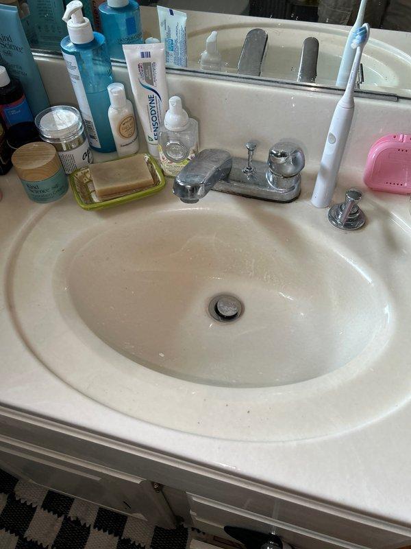 # Plumbing Inspection Summary

Completed comprehensive plumbing inspection as part of routine preventive maintenance service agreement. Inspected residential plumbing fixtures and infrastructure throughout the property, including bathroom facilities and basement utility areas.

## Findings and Observations

**Bathroom Fixtures:**
Inspected bathroom sink, faucet assembly, and drainage system. Two-handle chrome faucet with central spout operating properly with adequate water flow and pressure. Drain stopper functioning correctly with no visible leaks at basin connections. Fixture mounting secure and countertop area showing normal wear consistent with age. No immediate repairs required for bathroom plumbing fixtures.

**Basement Plumbing Infrastructure:**
Identified significant corrosion on vertical copper supply line at joint connection point in basement utility area. Corrosion presents as blue-green verdigris with crusty buildup and white deposits concentrated around cross-fitting conne