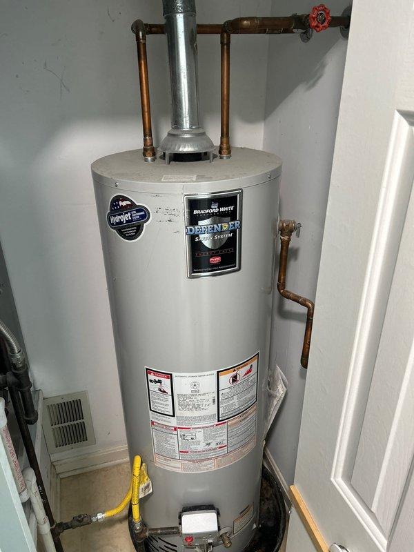 Conducted on-site evaluation of existing gas-fired Bradford White Defender System water heater located in upstairs utility closet. Documented current installation configuration including copper supply and distribution piping, gas line connections, venting system, and clearance requirements. Provided replacement estimate for new Bradford White tank-style gas water heater per customer request.