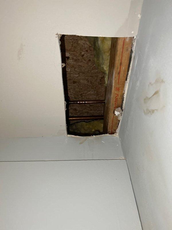 Responded to water leak originating from outdoor hose spigot penetrating into interior laundry room. Accessed wall cavity by creating drywall openings to trace leak source and assess extent of water intrusion. Located compromised connection point where exterior spigot piping penetrated wall assembly. Removed sections of drywall to expose framing, insulation, and plumbing components for proper diagnosis and repair access. Documented existing conditions including water-damaged insulation and structural framing requiring remediation.