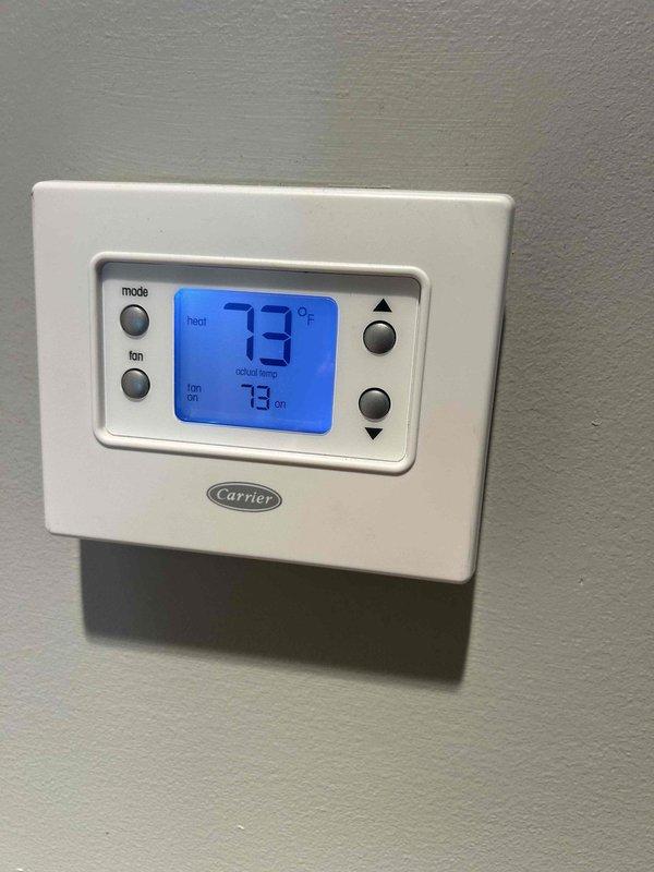 Responded to no cooling call on electric HVAC system that had been non-operational for several days. Upon arrival, found Carrier programmable thermostat displaying 73°F in heat mode rather than cooling mode. Performed system diagnostics on basement-located furnace and associated cooling components. Documented equipment specifications and clearances, noting 80.0 AFUE gas furnace with standard PVC condensate drainage. Filter had not been changed since January, which may have contributed to airflow restrictions. Assessed thermostat programming and system operation to determine root cause of cooling failure and restore proper functionality to the aging system.