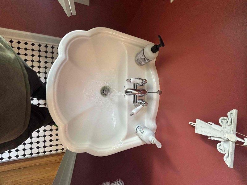 Completed comprehensive 60-point plumbing inspection of residential property and performed tanked water heater flush service. Inspection included evaluation of all accessible plumbing fixtures, supply lines, drain systems, and shut-off valves throughout the home. Examined bathroom sink with wall-mount installation, verified proper operation of chrome fixtures and cross-handle faucet controls, and inspected visible water supply lines for leaks or corrosion. Assessed kitchen double-basin stainless steel sink with single-handle faucet, checked under-sink plumbing connections and cabinet areas for moisture or damage. Flushed tanked water heater to remove sediment buildup and maintain optimal heating efficiency and equipment longevity. All systems found operating within normal parameters with no immediate repairs required.