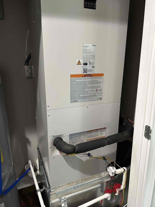 Completed full residential HVAC system installation including Bosch heat pump model BOVA60RTBM20, Bosch air handler model BIVA48RCBM20 with 15KW heat kit (L83-049), and Bosch communicating thermostat (L51-915). Relocated air handler to the left and installed new base box with built-in 1" filter rack to improve accessibility and filtration. Removed existing barrier in main return wall opening to enhance airflow into air handler and eliminate whistling noise caused by restricted return air passage.

Installed outdoor unit on concrete pad with snow legs for elevation and drainage, complete with electrical whip kit and disconnect box. Added surge protection and insulated refrigerant lines with inline filter for system protection. Mounted air handler in interior utility closet with proper transitions to existing ductwork. Installed comprehensive drain safety system including trap, SS2 coil drain safety water sensor, and "Ceiling Saver" overflow drain pan with secondary water sensor for leak