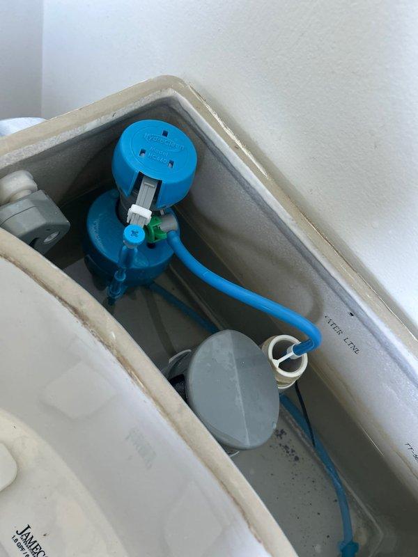 Completed full toilet rebuild including replacement of fill valve assembly and flapper mechanism. Installed new blue fill valve with refill tube and gray flapper valve with chain assembly to restore proper flush and fill operation. All components tested and functioning correctly upon completion.