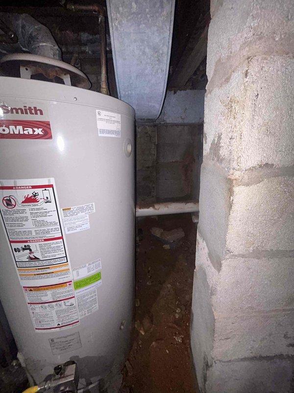 Conducted on-site plumbing estimate for water heater replacement in basement location. Assessed existing 50-gallon conventional tank water heater (Smith ProMax model) for conversion to tankless system. Evaluated current installation conditions including concrete block wall structure, existing plumbing connections, venting requirements, and electrical/gas utility access. Documented basement moisture conditions and floor staining that may require remediation consideration. Photographed existing water heater setup, surrounding piping infrastructure including copper and PVC lines, and available clearance space for potential tankless unit installation. Reviewed structural support requirements and determined necessary modifications for transitioning from tank to tankless configuration.