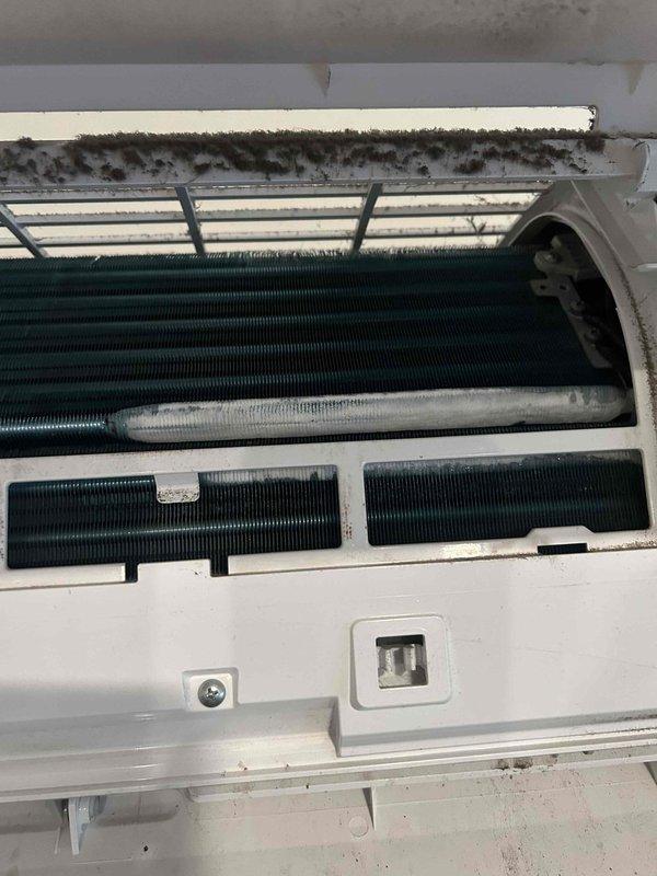 Responded to no cooling complaint on wall-mounted mini-split system in commercial kitchen. Upon inspection, found evaporator coil heavily contaminated with dust, dirt, and debris accumulation restricting airflow and reducing heat transfer efficiency. Removed front cover and accessed internal components. Cleaned evaporator coil assembly thoroughly, removing built-up contamination from fins and backing plates. Verified unit now cooling properly with adequate airflow through vents. Recommended more frequent filter maintenance to prevent future coil fouling.