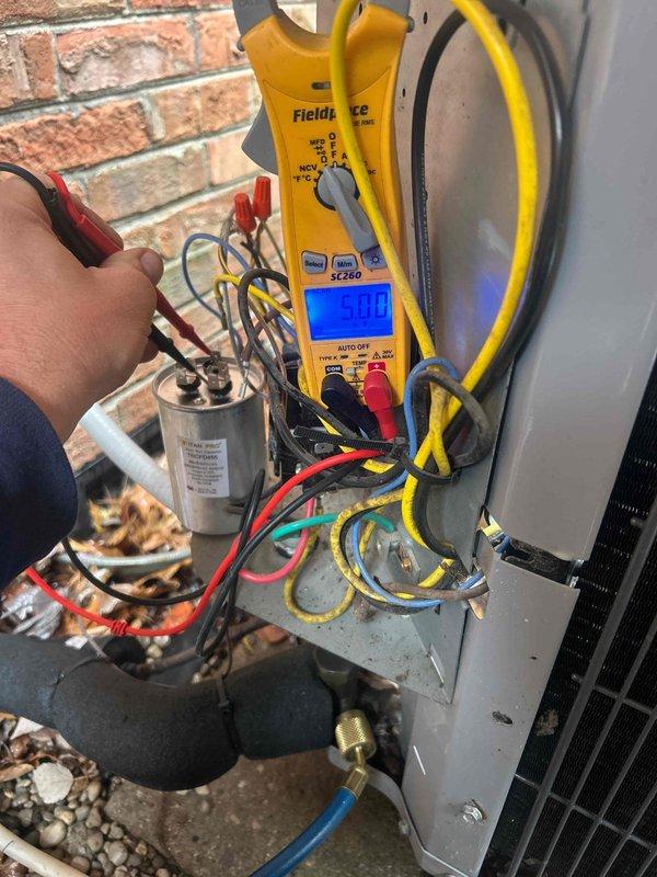 Completed scheduled preventive maintenance tune-up on approximately 10-year-old air conditioning system located in crawlspace. Performed comprehensive electrical diagnostics using digital multimeter and clamp meter on outdoor condensing unit. Verified voltage readings at electrical panel, tested capacitor operation, and measured amperage draw showing 304.5 amps on compressor circuit. Inspected all wire connections including red, black, yellow, blue, green, and white conductors at terminal block. Confirmed proper electrical values and secure connections throughout system. Customer provided their own 16x25x4 air filter as specified. System operating within normal parameters upon completion of maintenance service.