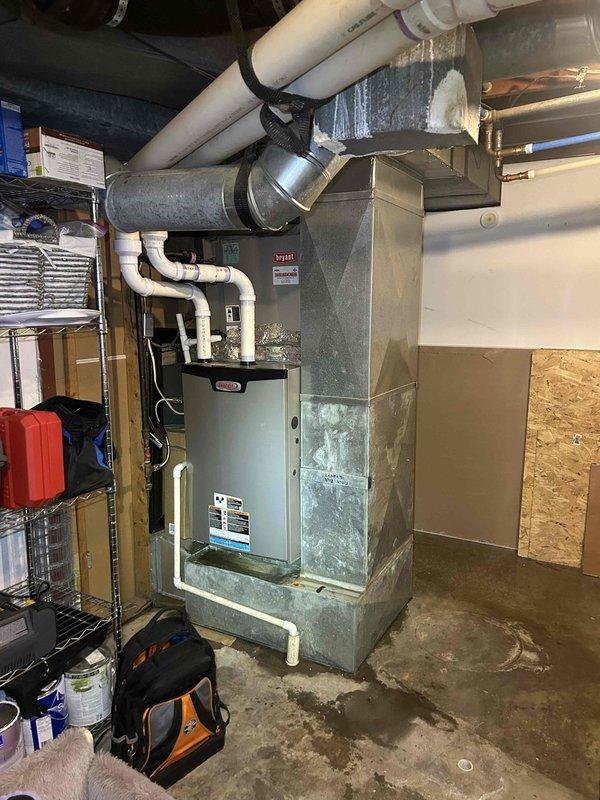 Responded to no-cooling complaint on aging air conditioning system paired with 2-year-old Bryant gas furnace in basement location. Customer reported unit unable to maintain temperature below 75 degrees during warm weather over the past several days. Performed diagnostic evaluation of complete HVAC system including inspection of indoor air handler, refrigerant lines, ductwork connections, and electrical components. Documented equipment conditions with photographic evidence showing existing installation configuration, PVC condensate drainage system, flexible duct connections, and overall mechanical room layout for service records.